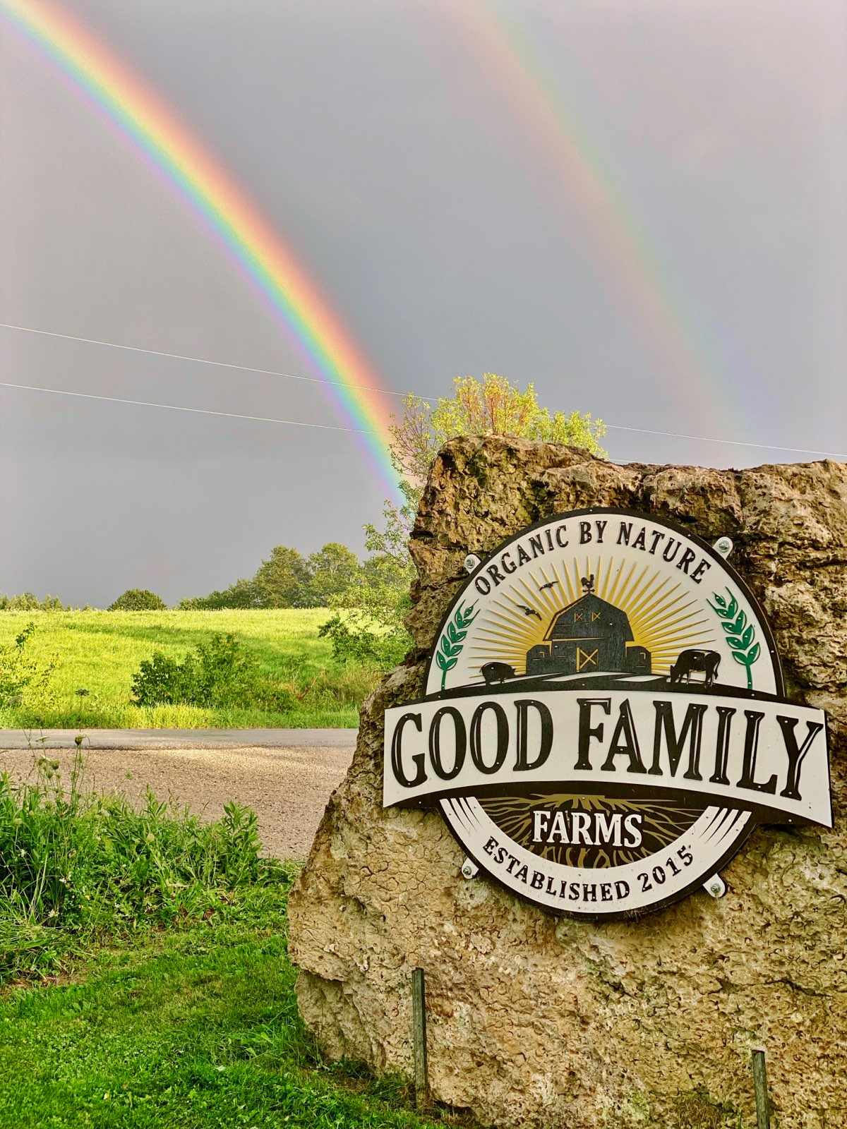 Good Family Farms sign at the farm entrance under a double rainbow